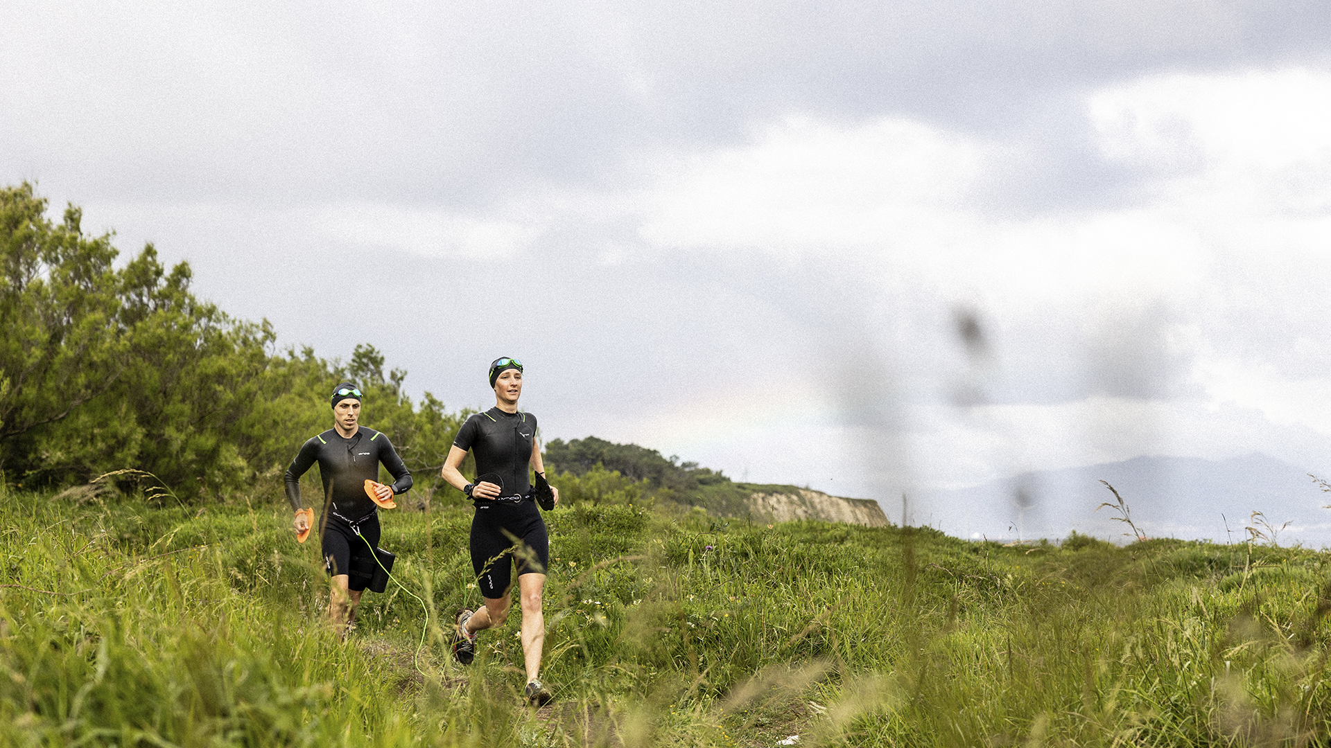 Dvaja swimrun bežci v zelenej krajine nad pobrežím